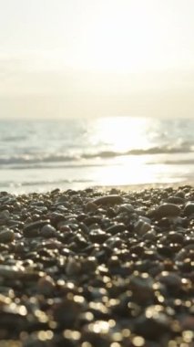 A yellow Easter Egg lies on a pebble by the sea. Sunset sun behind, close-up. the focus slowly shifts to the Egg. Vertical video Social Media