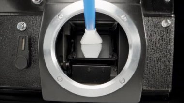 I clean the mirror of an old camera with a special wand, close-up
