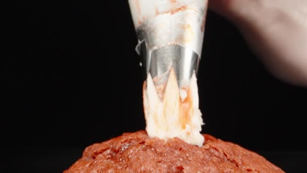 黒の背景にカップケーキの上にクリームを絞る ドリースライダー極端なクローズアップ ラオワプローブ — ストック動画
