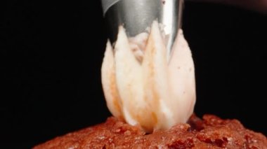 Squeezing cream on a cupcake, on a black background. Dolly slider extreme close-up. Laowa Probe