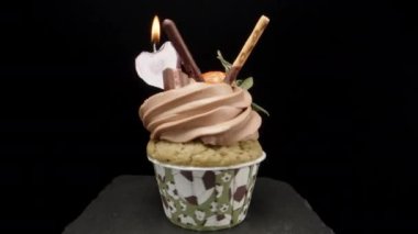 Cupcake with a heart-shaped candle and strawberries with chocolate. Rotation on the table.