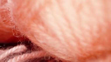 A ball of pink woolen threads, on black glass.. Dolly slider extreme close-up. Laowa Probe