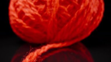 A ball of red woolen threads on black glass.. Dolly slider extreme close-up. Laowa Probe