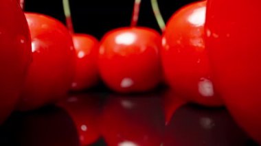 Artificial plastic, red cherries, on a black table. Dolly slider extreme close-up. Laowa Probe