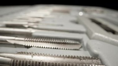 A set of taps for cutting threads in metal in a box. Dolly slider extreme close-up. Laowa Probe
