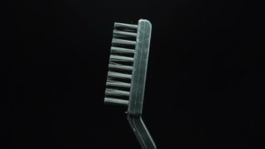 Black plastic hand-scrubbing brush rotating on a black background.