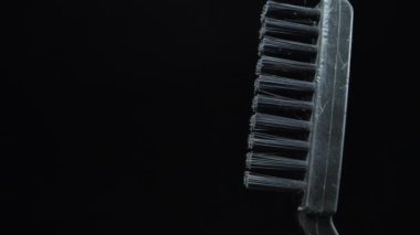 Black plastic hand-scrubbing brush rotating on a black background. Dolly slider extreme close-up. Laowa Probe