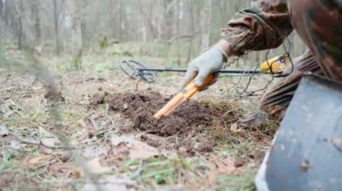 A man in camouflage with a metal detector found an old cork. Search for treasures, coins, metal.