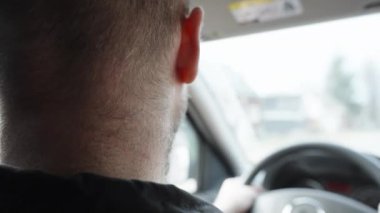 Bearded man with short haircut driving, close-up rear view.