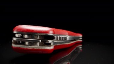 Red folding knife, on a black glass table, close-up.