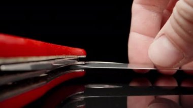 Red folding knife on black glass. I fold the blade .Dolly slider extreme close-up. Laowa Probe