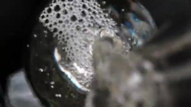 I pour clean water from a glass bottle, the camera is inside the glass, top view. Slider Dolly extreme close-up inside. Laowa Probe