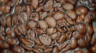 Roasted whole coffee beans that float and swirl in the drink. Macro shooting, slow motion