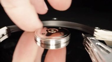 Disassembled computer hard drive, on a black background. You cant do repairs like that, I touch the surface of the disk with my finger, close-up.