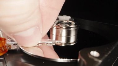 Disassembled computer hard drive, on a black background. You cant do repairs like that, I touch the surface of the disk with my finger, close-up.