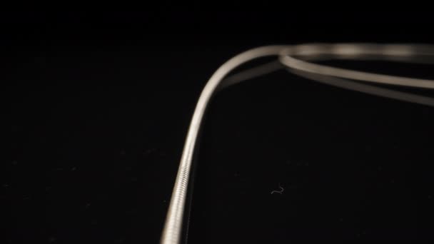 吉他上的金属线卷曲在一张黑色桌子上 — 图库视频影像