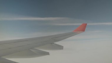 The wing of the plane is in the clouds. The plane turns.