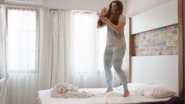 Sunny morning, bright room. The young woman jumps on the bed and scatters banknotes, Turkish lira. Slow mo