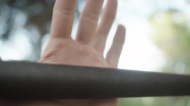 Male hand with callosity from playing sports on the horizontal bar, close-up. Hand holding on to a metal rod