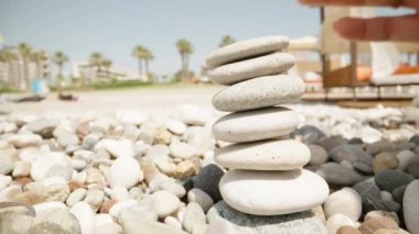 Yakın plan, bir kadın cairn yapıyor. Deniz kıyısında el yapımı taş kule. Kumsalda dengeli çakıl yığınları.