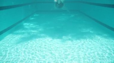 Blue swimming pool, underwater shooting, sunny day. A plump young woman swims in a closed swimsuit