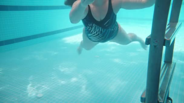 青いスイミングプール 水中撮影 晴れた日 豊満な若い女性は水から階段を上る — ストック動画