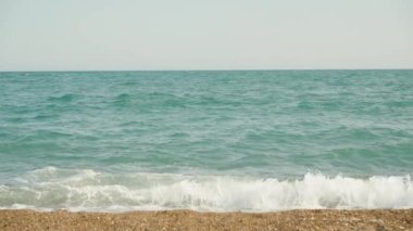 The blue sea is storming. The waves hit the shore. Slow mo