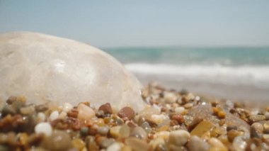 Stones on the sea beach are covered with a wave. Super macro, slow mo.