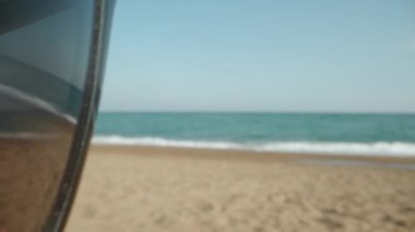 A young woman on the beach. The sea is reflected in the glasses. Dolly slider extreme close-up. Laowa Probe