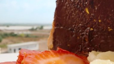 Breakfast under the open sky on the balcony on a sunny morning. Chocolate bread, strawberry and banana sandwich. Dolly slider extreme close-up. Laowa Probe. Slow mo