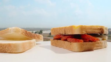 Breakfast under the open sky on the balcony on a sunny morning. Bite chocolate sandwich with fruits