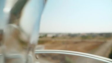 Pouring water into a blue clear glass against the blue sky. Dolly slider extreme close-up. Laowa Probe. Slow mo