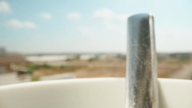 Boiling water is poured into a white mug. Coffee is brewed. Against the blue sky. Dolly slider extreme close-up. Laowa Probe. Slow mo