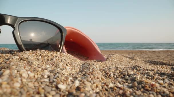 Γυαλιά Ηλίου Και Ροζ Σαγιονάρες Βρίσκονται Στην Άμμο Στο Φόντο — Αρχείο Βίντεο