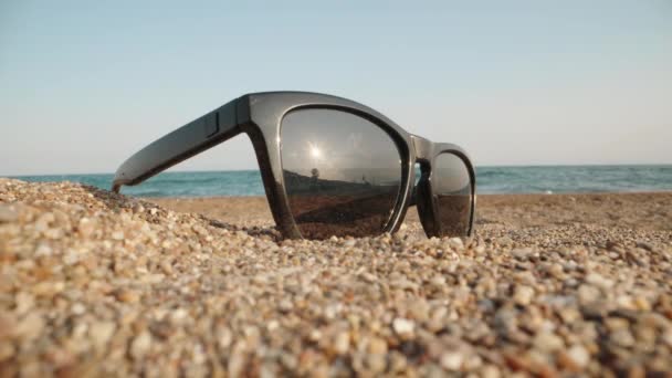 Sunglasses Lie Sand Background Sea Sun Reflected Glasses Close Laowa — Stockvideo
