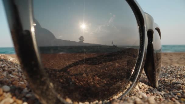 Γυαλιά Ηλίου Βρίσκονται Στην Άμμο Στο Φόντο Της Θάλασσας Ήλιος — Αρχείο Βίντεο