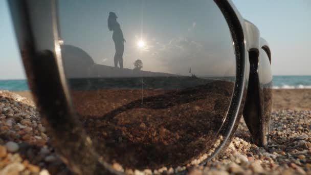 Γυαλιά Ηλίου Βρίσκονται Στην Άμμο Στο Φόντο Της Θάλασσας Νεαρή — Αρχείο Βίντεο
