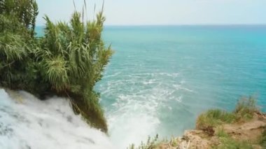Türkiye 'nin Antalya ilinin Akdeniz kıyısındaki Duden şelalesi ve Duden parkı. Güneşli bir günde masmavi suyla deniz manzarası ve dik bir kaya..