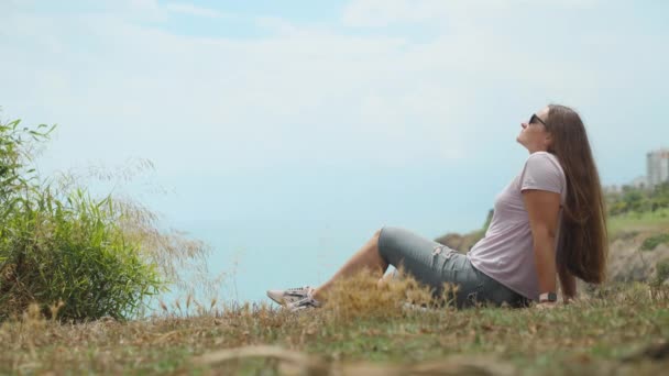 Gözlüklü Genç Bir Kadın Uçurumun Kenarında Oturuyor Deniz Manzaralı — Stok video