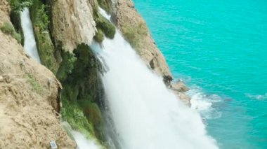 The waterfall flows into the sea. Blue water. Slow mo