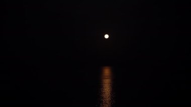 Strawberry supermoon over the sea. Reflection on the water. The boat sails in the light of the moon