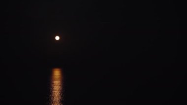 Strawberry supermoon over the sea. Reflection on the water. The boat sails in the light of the moon
