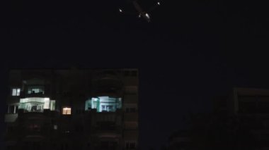 The plane flies over the building, nightly shooting.