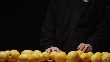 Siyahlı adam masaya çok sayıda limonla yaklaşır, üç limon alır ve onlarla hokkabazlık yapar. Yavaş çekim.
