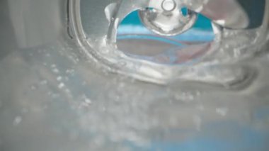 Soda is poured from a can into a glass. The sea is in the background. Summer, sunny day, beach. View inside the can.