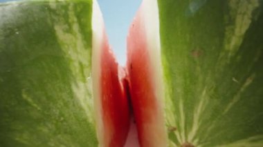 Karpuz ikiye bölünmüş ve kamera içeride kayıtta. Mavi gökyüzüne karşı. Dolly Slider aşırı yakın çekim. Laowa Sondası. Yavaş çekim