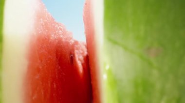 Karpuz ikiye bölünmüş ve kamera içeride kayıtta. Mavi gökyüzüne karşı. Dolly Slider aşırı yakın çekim. Laowa Sondası. Yavaş çekim