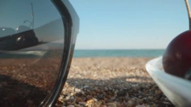 Sahilde bir tabak dut, deniz. Kirazlı ve dutlu çilek. Gözlüklerdeki yansıma. Dolly Slider aşırı yakın çekim. Laowa Sondası. Yavaş çekim