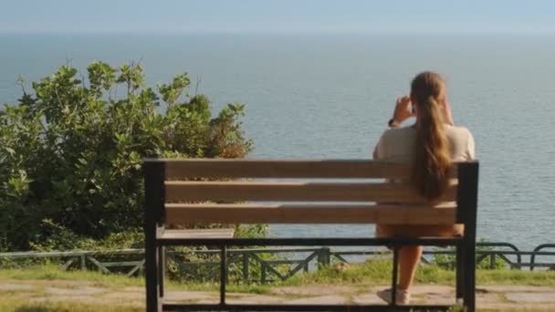 Молода Жінка Сидить Лавці Узбережжі Фотографує Пейзаж Вид Море Літо — стокове відео