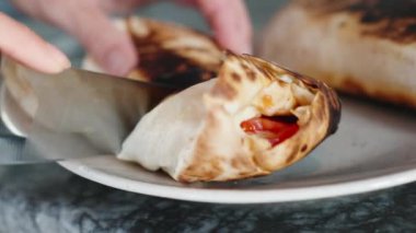 Pişirirken, tabakta kızarmış shawarma kestim. Harekete geç. Siyah taş tezgah..